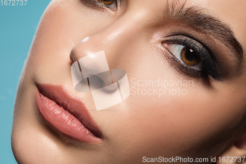 Image of Close up of female fashion model\'s face isolated on blue studio background. Style and beauty concept.