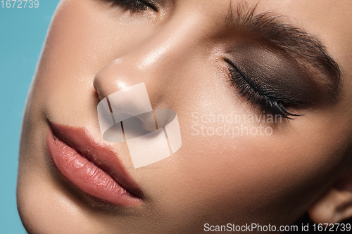 Image of Close up of female fashion model\'s face isolated on blue studio background. Style and beauty concept.