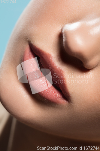 Image of Close up of female fashion model\'s face isolated on blue studio background. Style and beauty concept.