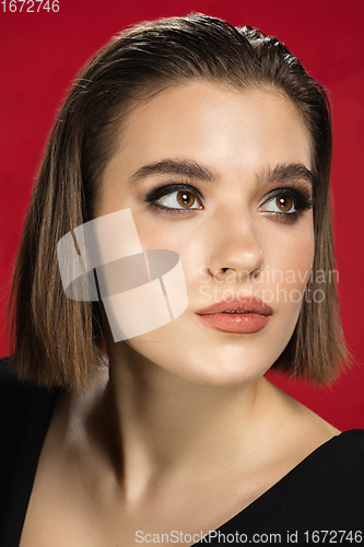 Image of Portrait of female fashion model isolated on red studio background. Style and beauty concept. Close up.