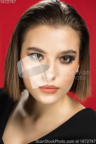Image of Portrait of female fashion model isolated on red studio background. Style and beauty concept. Close up.