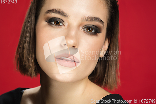 Image of Portrait of female fashion model isolated on red studio background. Style and beauty concept. Close up.