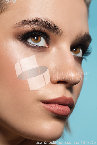 Image of Close up of female fashion model\'s face isolated on blue studio background. Style and beauty concept.