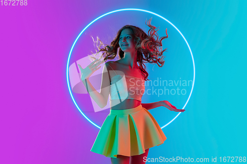 Image of Beautiful girl in fashionable, romantic outfit on gradient background in neon light with glowing neoned blue circle