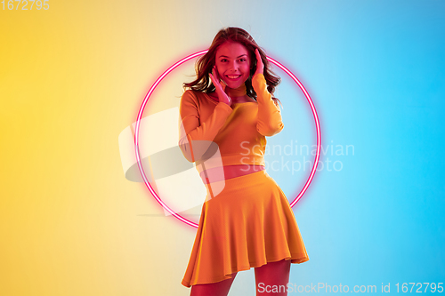 Image of Beautiful girl in fashionable, romantic outfit on gradient background in neon light with glowing neoned pink circle