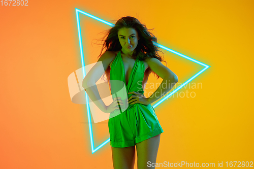 Image of Beautiful seductive girl in fashionable, romantic outfit on gradient background in neon light with glowing neoned blue triangle