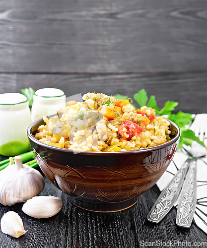 Image of Barley porridge with minced meat in bowl on black wooden board