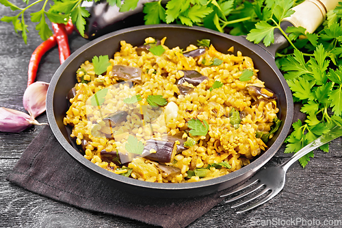 Image of Bulgur with eggplant in pan on dark board