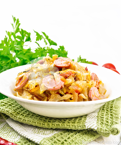 Image of Cabbage stew with sausages in white plate on wooden board