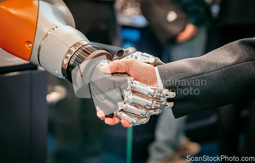 Image of Hand of a businessman shaking hands with a Android robot.