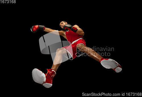 Image of Young african-american boxer in action, motion isolated on black background, look from the bottom. Concept of sport, movement, energy and dynamic.