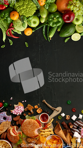 Image of Fast and healthy food compared on black stone background. Unhealthy set including burgers, sauces, french fries in comparison with vegetables, fruits, organic food