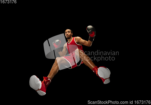 Image of Young african-american boxer in action, motion isolated on black background, look from the bottom. Concept of sport, movement, energy and dynamic.