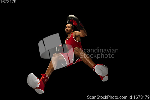 Image of Young african-american boxer in action, motion isolated on black background, look from the bottom. Concept of sport, movement, energy and dynamic.