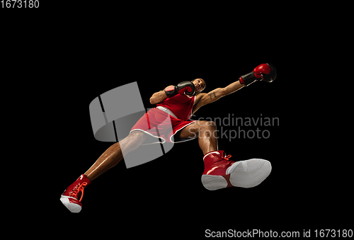 Image of Young african-american boxer in action, motion isolated on black background, look from the bottom. Concept of sport, movement, energy and dynamic.