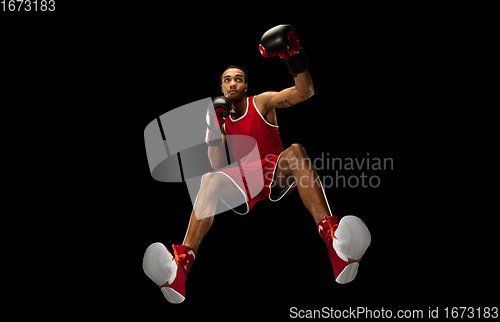 Image of Young african-american boxer in action, motion isolated on black background, look from the bottom. Concept of sport, movement, energy and dynamic.