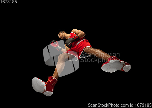 Image of Young african-american boxer in action, motion isolated on black background, look from the bottom. Concept of sport, movement, energy and dynamic.