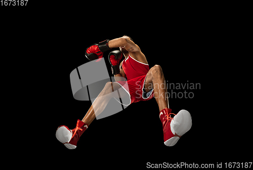 Image of Young african-american boxer in action, motion isolated on black background, look from the bottom. Concept of sport, movement, energy and dynamic.