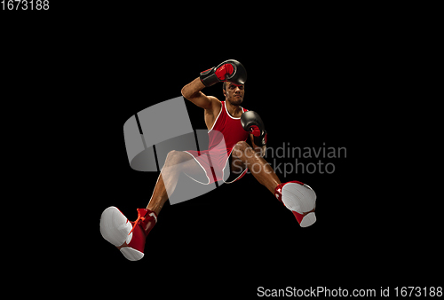 Image of Young african-american boxer in action, motion isolated on black background, look from the bottom. Concept of sport, movement, energy and dynamic.