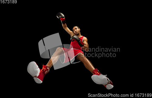 Image of Young african-american boxer in action, motion isolated on black background, look from the bottom. Concept of sport, movement, energy and dynamic.