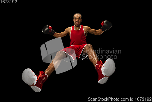 Image of Young african-american boxer in action, motion isolated on black background, look from the bottom. Concept of sport, movement, energy and dynamic.