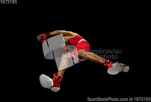 Image of Young african-american boxer in action, motion isolated on black background, look from the bottom. Concept of sport, movement, energy and dynamic.