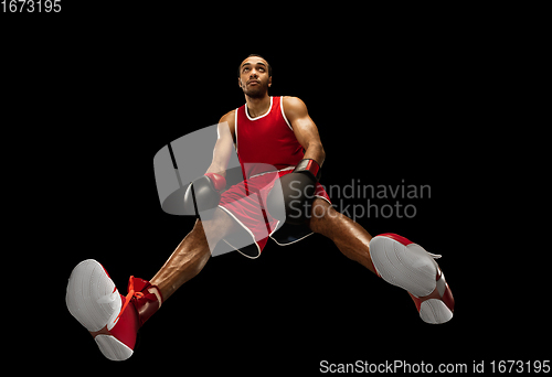 Image of Young african-american boxer in action, motion isolated on black background, look from the bottom. Concept of sport, movement, energy and dynamic.