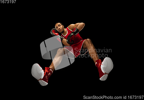 Image of Young african-american boxer in action, motion isolated on black background, look from the bottom. Concept of sport, movement, energy and dynamic.