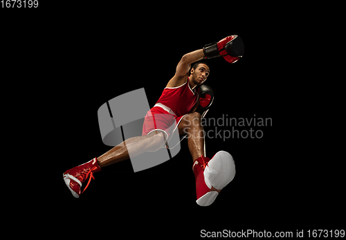 Image of Young african-american boxer in action, motion isolated on black background, look from the bottom. Concept of sport, movement, energy and dynamic.