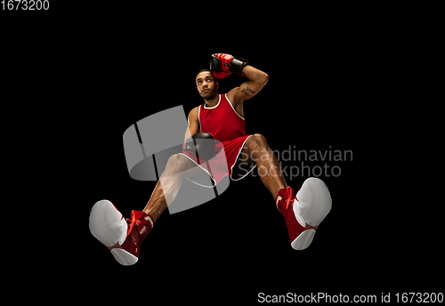 Image of Young african-american boxer in action, motion isolated on black background, look from the bottom. Concept of sport, movement, energy and dynamic.