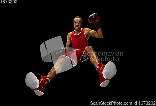 Image of Young african-american boxer in action, motion isolated on black background, look from the bottom. Concept of sport, movement, energy and dynamic.