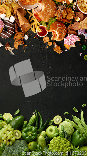 Image of Fast and healthy food compared on black stone background. Unhealthy set including burgers, sauces, french fries in comparison with vegetables, fruits, organic food