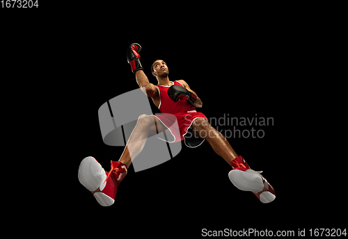 Image of Young african-american boxer in action, motion isolated on black background, look from the bottom. Concept of sport, movement, energy and dynamic.