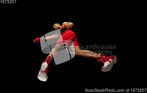 Image of Young african-american boxer in action, motion isolated on black background, look from the bottom. Concept of sport, movement, energy and dynamic.