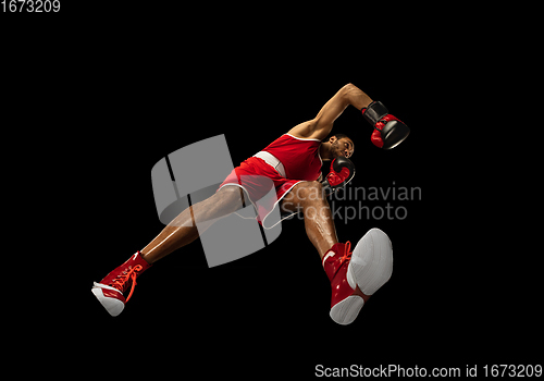 Image of Young african-american boxer in action, motion isolated on black background, look from the bottom. Concept of sport, movement, energy and dynamic.