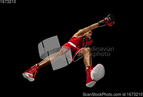 Image of Young african-american boxer in action, motion isolated on black background, look from the bottom. Concept of sport, movement, energy and dynamic.