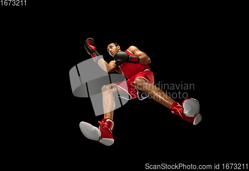 Image of Young african-american boxer in action, motion isolated on black background, look from the bottom. Concept of sport, movement, energy and dynamic.