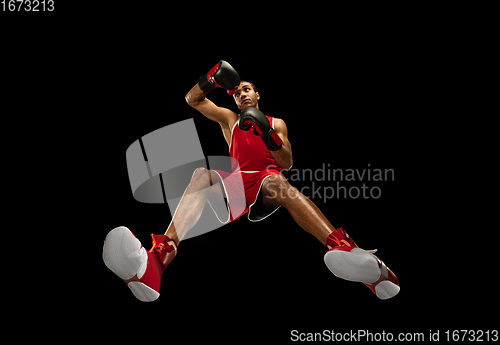 Image of Young african-american boxer in action, motion isolated on black background, look from the bottom. Concept of sport, movement, energy and dynamic.