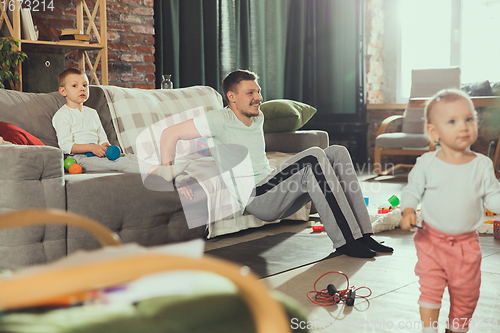 Image of Young man exercising fitness, aerobic, yoga at home, sporty lifestyle. Getting active while his child playing on the background, home gym.