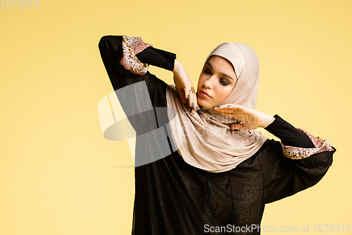 Image of Beautiful arab woman posing in stylish hijab isolated on yellow studio background. Fashion, beauty, style concept