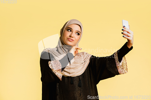 Image of Beautiful arab woman posing in stylish hijab isolated on yellow studio background. Fashion, beauty, style concept