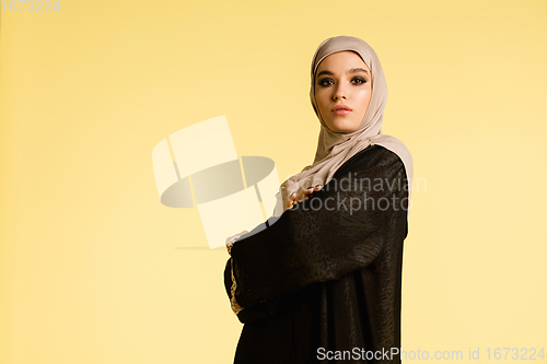 Image of Beautiful arab woman posing in stylish hijab isolated on yellow studio background. Fashion, beauty, style concept