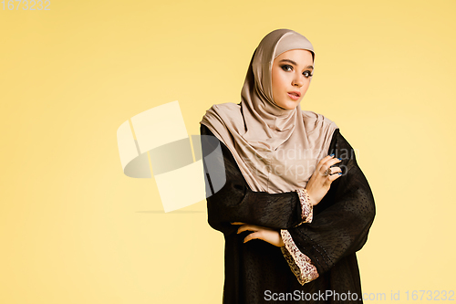 Image of Beautiful arab woman posing in stylish hijab isolated on yellow studio background. Fashion, beauty, style concept