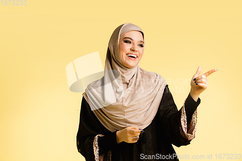 Image of Beautiful arab woman posing in stylish hijab isolated on yellow studio background. Fashion, beauty, style concept