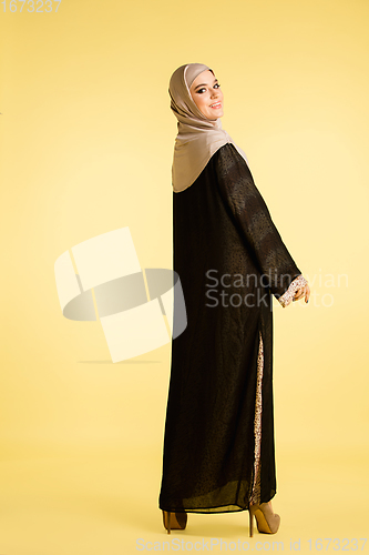Image of Beautiful arab woman posing in stylish hijab isolated on yellow studio background. Fashion, beauty, style concept