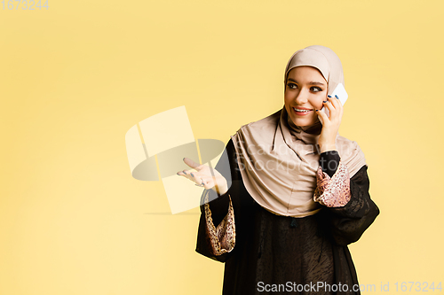 Image of Beautiful arab woman posing in stylish hijab isolated on yellow studio background. Fashion, beauty, style concept
