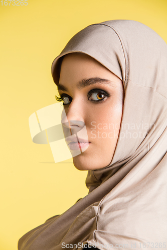 Image of Beautiful arab woman posing in stylish hijab isolated on yellow studio background. Fashion, beauty, style concept