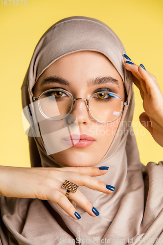Image of Beautiful arab woman posing in stylish hijab isolated on yellow studio background. Fashion, beauty, style concept
