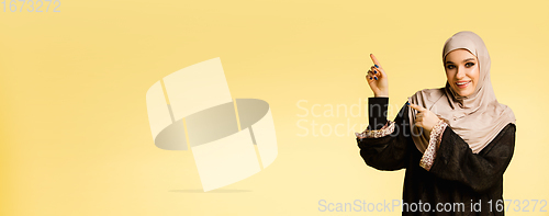 Image of Beautiful arab woman posing in stylish hijab isolated on yellow studio background. Fashion, beauty, style concept