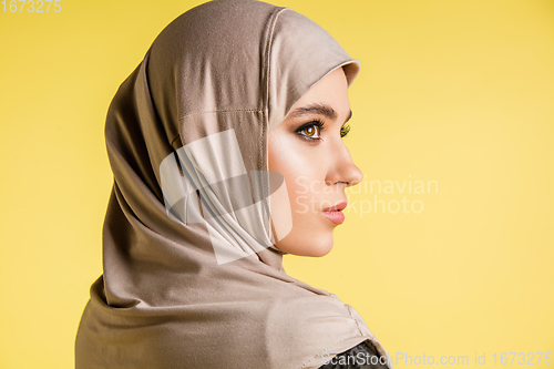 Image of Beautiful arab woman posing in stylish hijab isolated on yellow studio background. Fashion, beauty, style concept